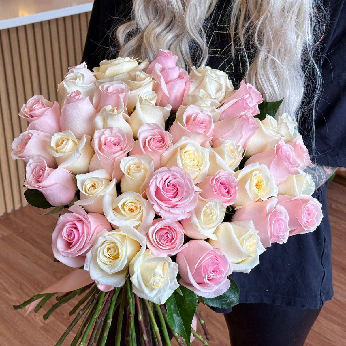 White and Light Pink Long-Stem Roses Bouquet held by florist, 50 stems pictured