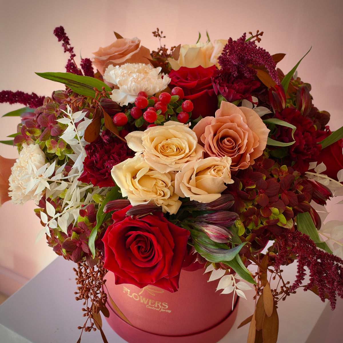 Close-up of the FREA flower box with red roses, beige roses and burgundy amaranthus